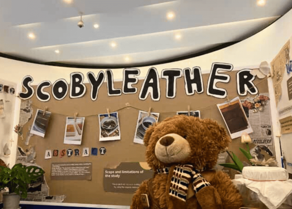 SPR BFITS Program science expo display board for “Scoby Leather,” with photos clipped on a brown backdrop and a teddy bear in front